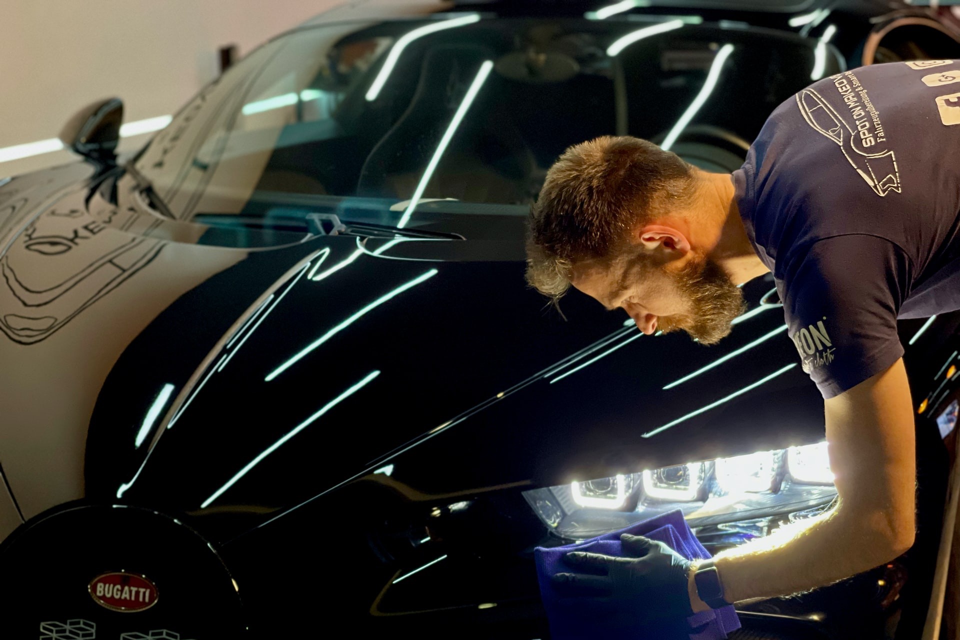 man in blue crew neck t-shirt standing beside black car
